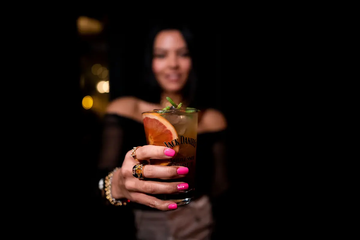 Stilfull kvinne som holder en cocktail i hånden om natten, utstråler eleganse og raffinement