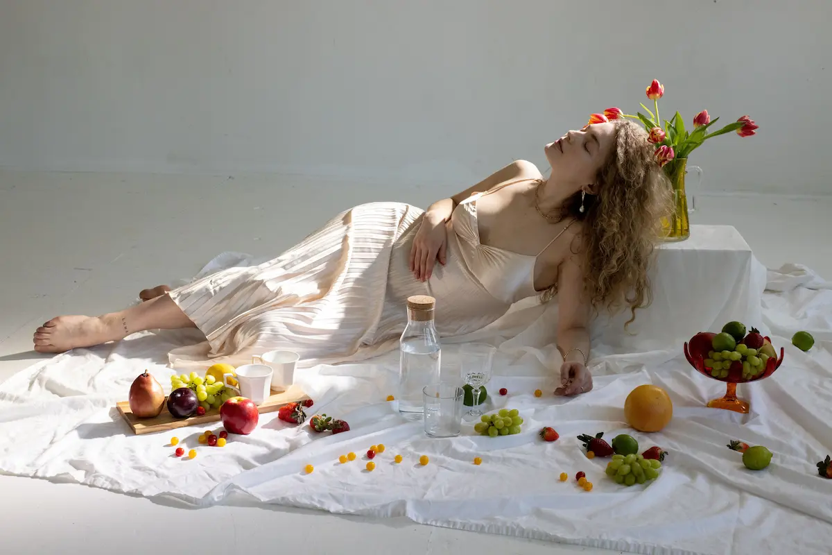 Multivitamin og omega-3: Elegant kvinne i rolige innendørs omgivelser med frisk frukt og blomster, som symboliserer velvære, balanse og en sunn livsstil med naturlige kosttilskudd.