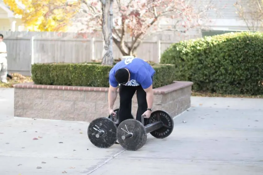 Farmers walk opptak med flat rygg og fast grep om en vekt på hver side