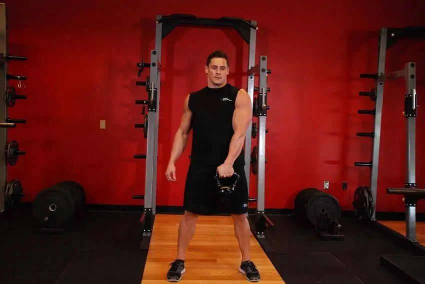 Kettlebell swing startposisjon med hoften bøyd bak og kula svingt mellom beina i ett grep