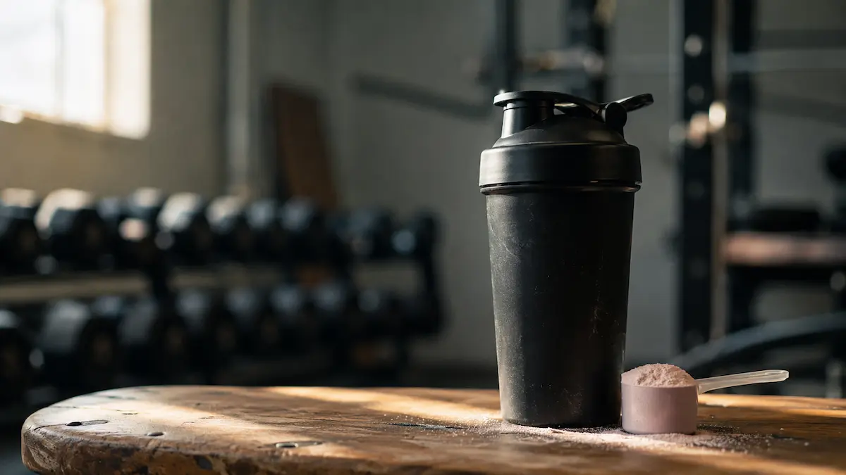 Person som tar benkpress i et uskarpt treningssenter, illustrasjon til guide om pre-workout uten koffein
