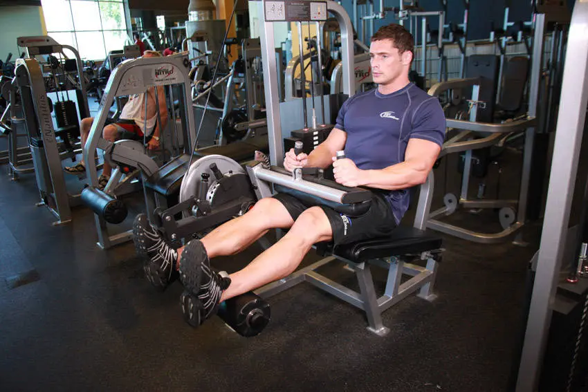 Leg curl startposisjon sittende i maskin med nesten strake ben over den nedre puten