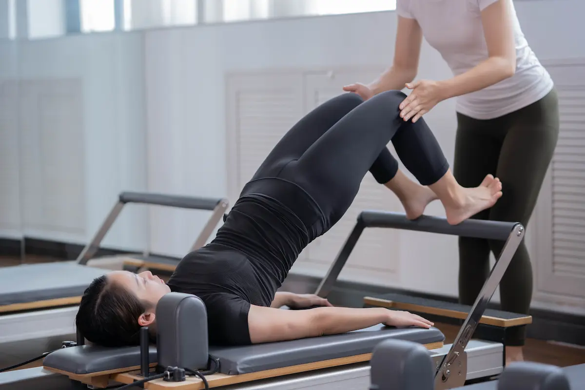Kvinner som trener reformer Pilates med instruktør i Shenzhen-studio for sunn livsstil