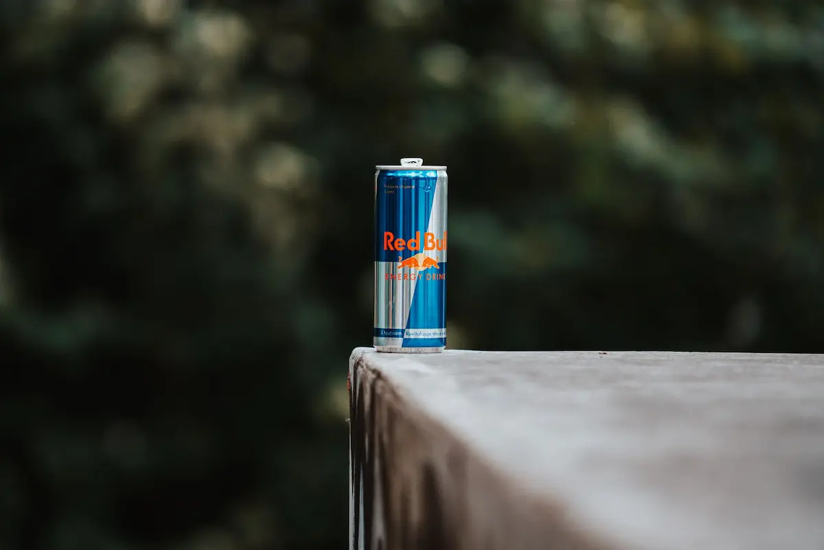 En boks med energidrikk på en avsats med en uskarp naturbakgrunn, som viser en sommerlig stemning.