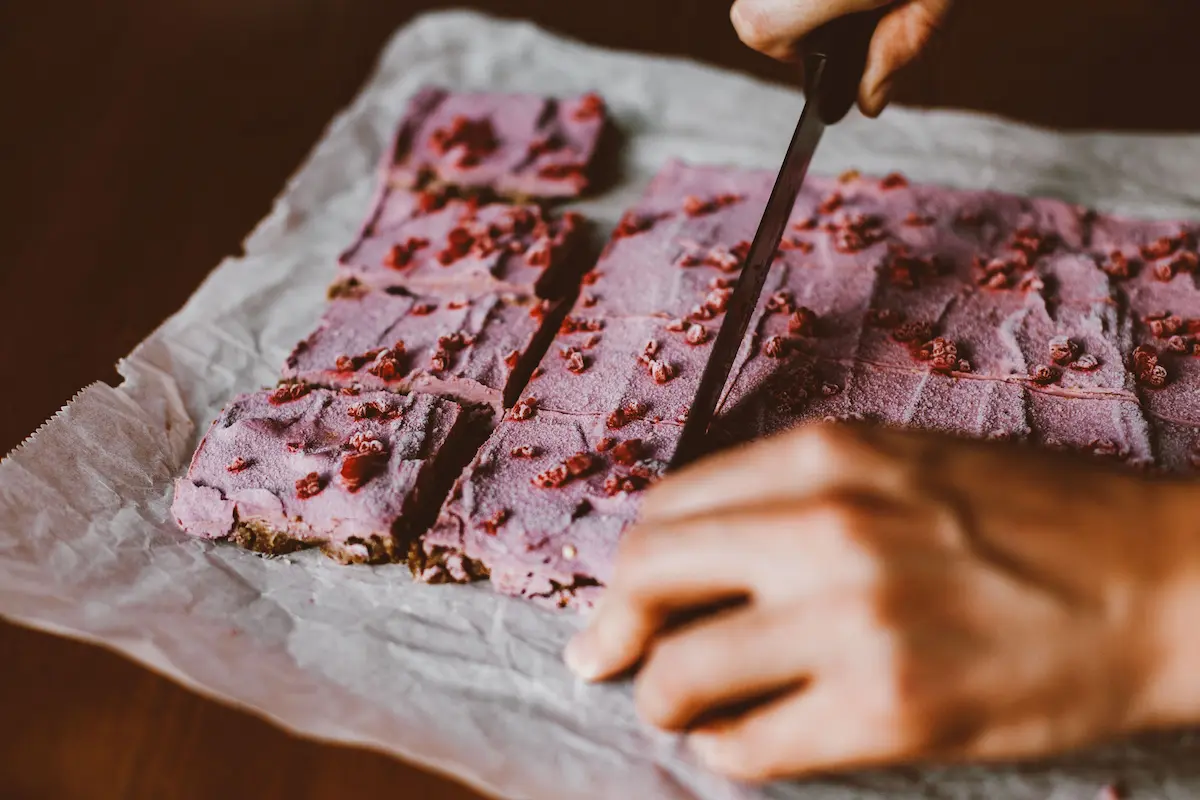 Hjemmelagde proteinbarer med bringebær skåret i biter på bakepapir